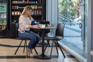 girl measures blood pressure while sitting in a cafeteria